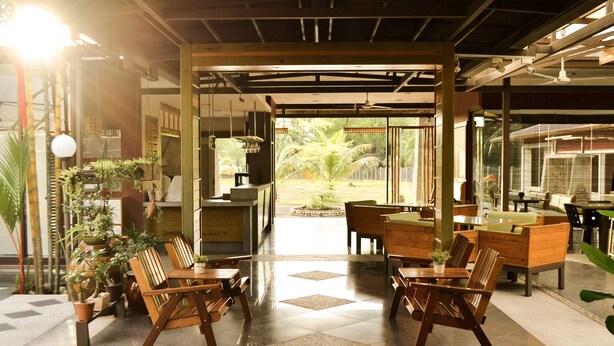 A spacious indoor area with wooden furniture, potted plants, and a view of the outdoors. - Qi Hotel and Club (Kota Kinabalu)