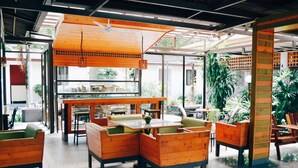 A restaurant with wooden furniture, a central table, and a ceiling fan. - Qi Hotel and Club (Kota Kinabalu)