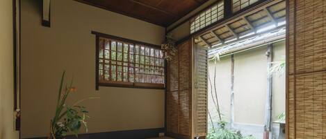 A traditional Japanese room with tatami flooring, a shoji screen, and a potted plant.