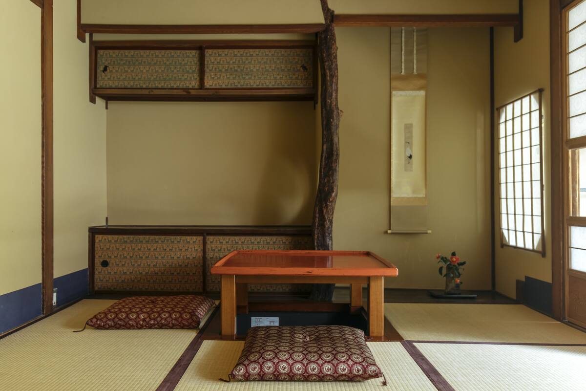 Une pièce de style japonais traditionnel, avec un sol recouvert de tatamis, une petite table en bois et des coussins.