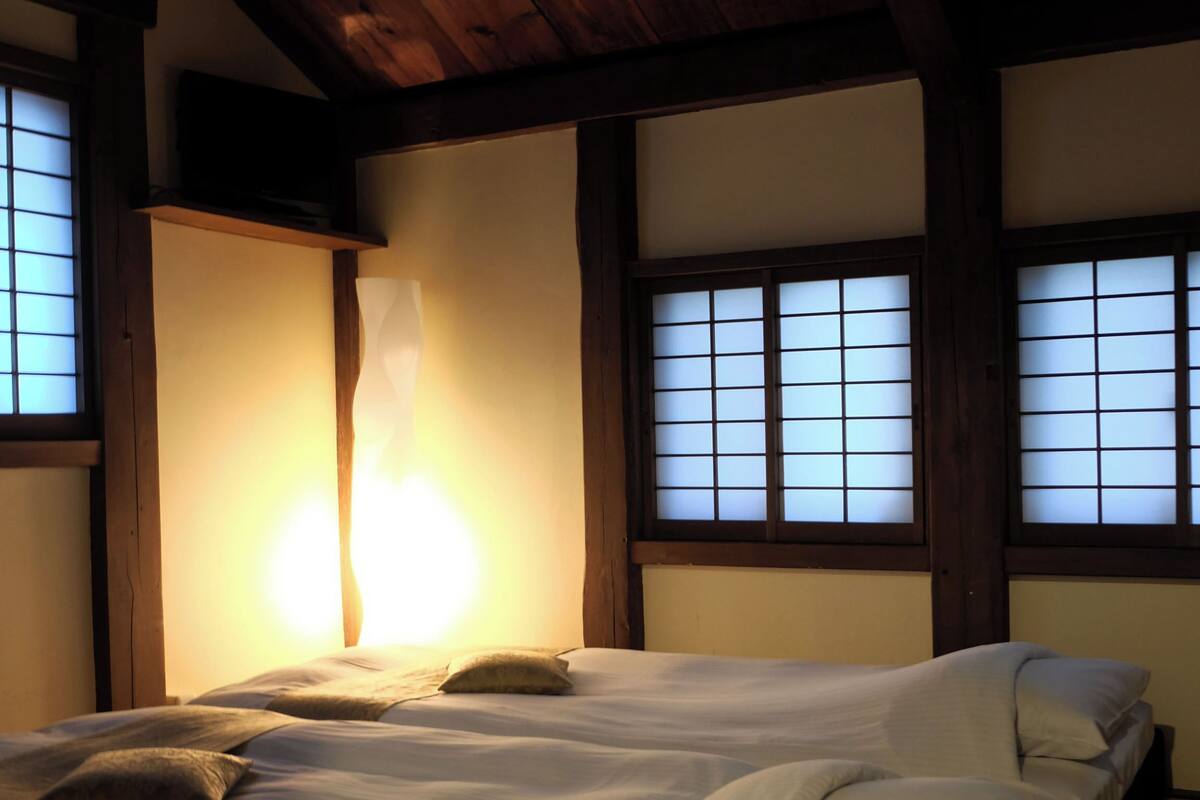 Une pièce de style japonais traditionnel, avec un sol recouvert de tatamis, un plafond bas en bois et des portes coulissantes en papier de riz (shoji).