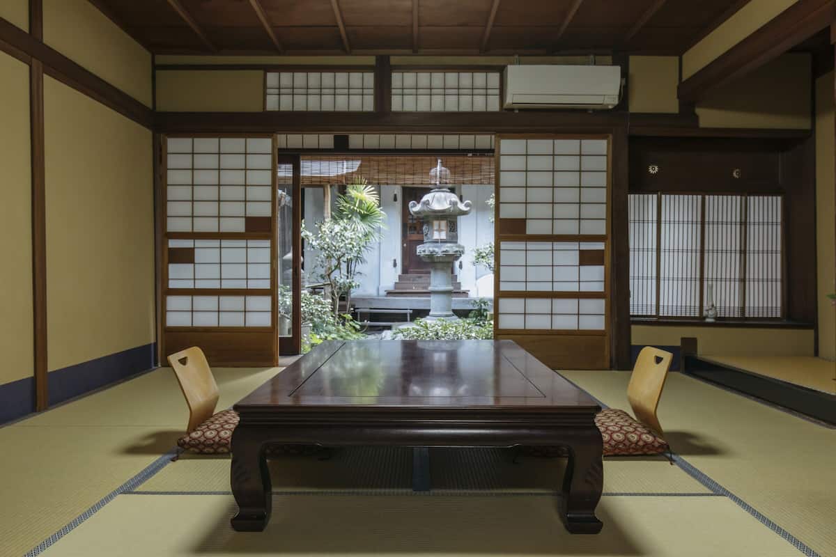 Une pièce de style japonais traditionnel, avec un sol recouvert de tatamis, une table basse et des paravents en papier de riz (shoji).