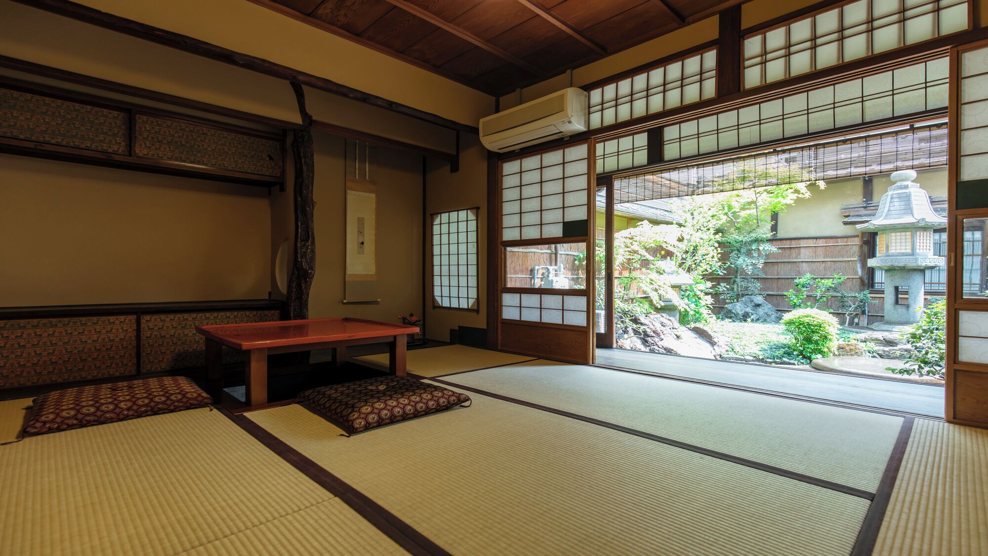 Une pièce de style japonais traditionnel, avec un sol recouvert de tatamis, une basse table en bois et des portes coulissantes donnant sur un jardin.