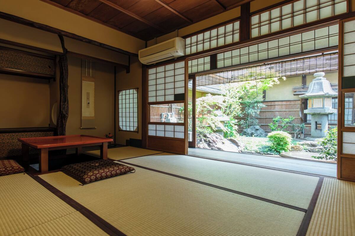 Une pièce de style japonais traditionnel, avec un sol recouvert de tatamis, une basse table en bois et des portes coulissantes donnant sur un jardin.