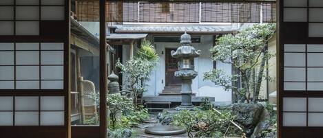 A traditional Japanese garden with a stone lantern, bamboo, and a small pond.