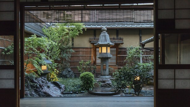 Ein traditioneller japanischer Garten mit einem Steintorii, Bambus und einem kleinen Teich.