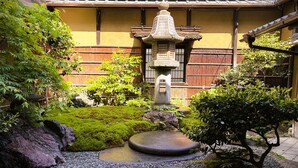 Ein traditioneller japanischer Garten mit einem Steinlaternen, Felsformationen und gepflegtem Grün.