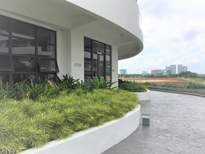 A modern building with a gym sign, large windows, and a landscaped area with plants.