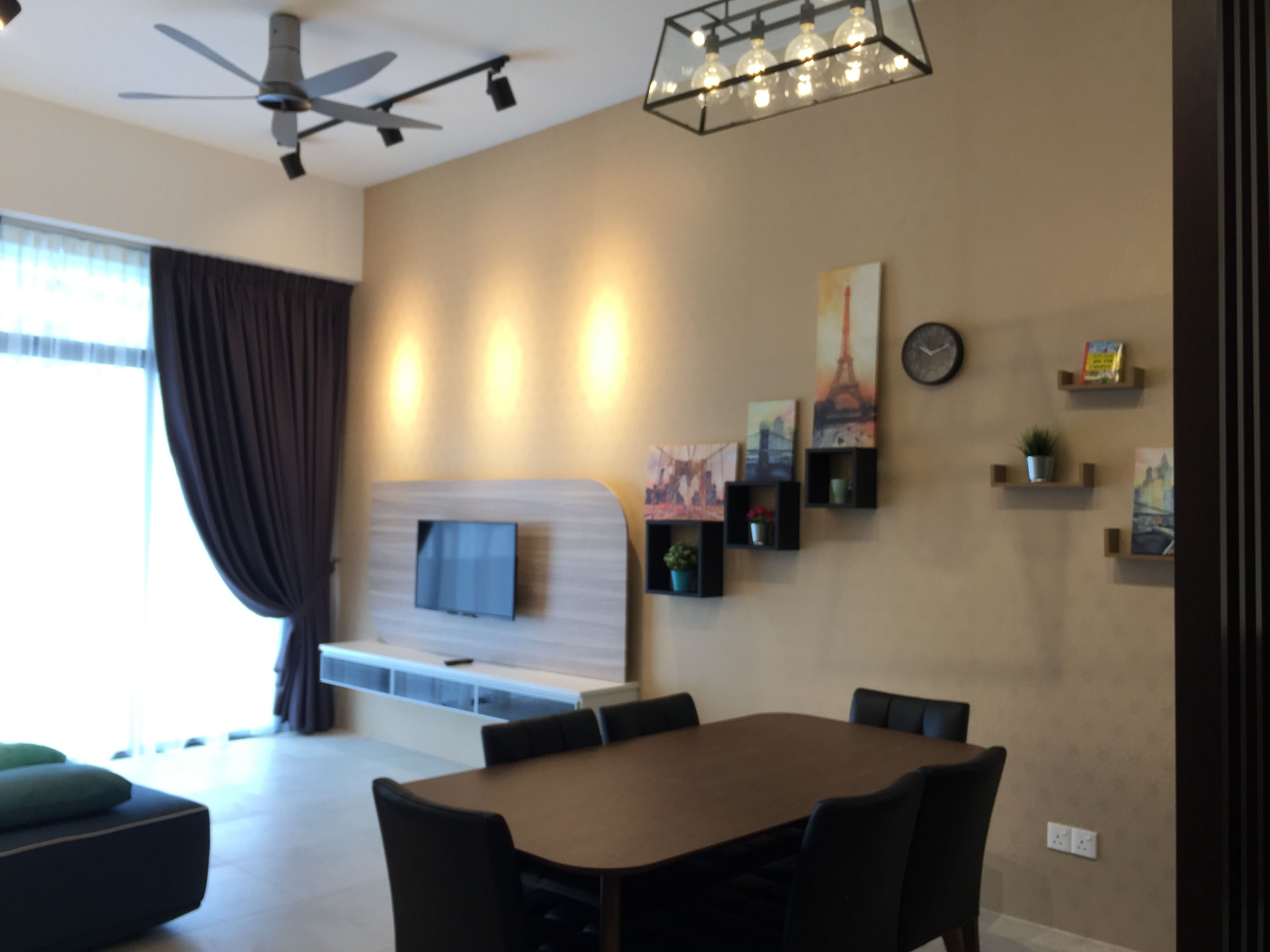 A modern living room with a dining area, a ceiling fan, a mounted TV, and wall-mounted shelves with decorative items.