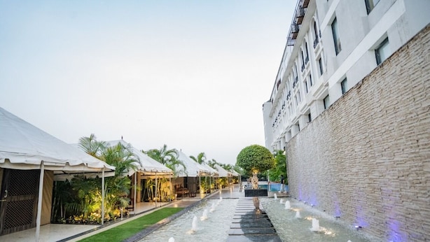 A courtyard with a water feature, outdoor seating, and a building with a stone facade. - Pride Hotel & Convention Centre Indore (Indore)