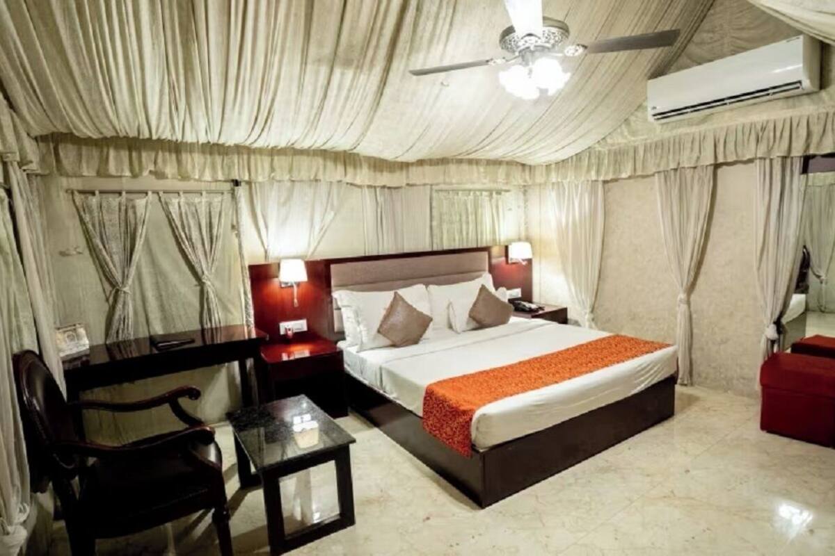 A hotel room with a bed, bedside tables, a desk, and a chair.