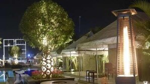 An outdoor area with a pool, a large planter with a tree, and a modern light fixture. - Pride Hotel & Convention Centre Indore (Indore)