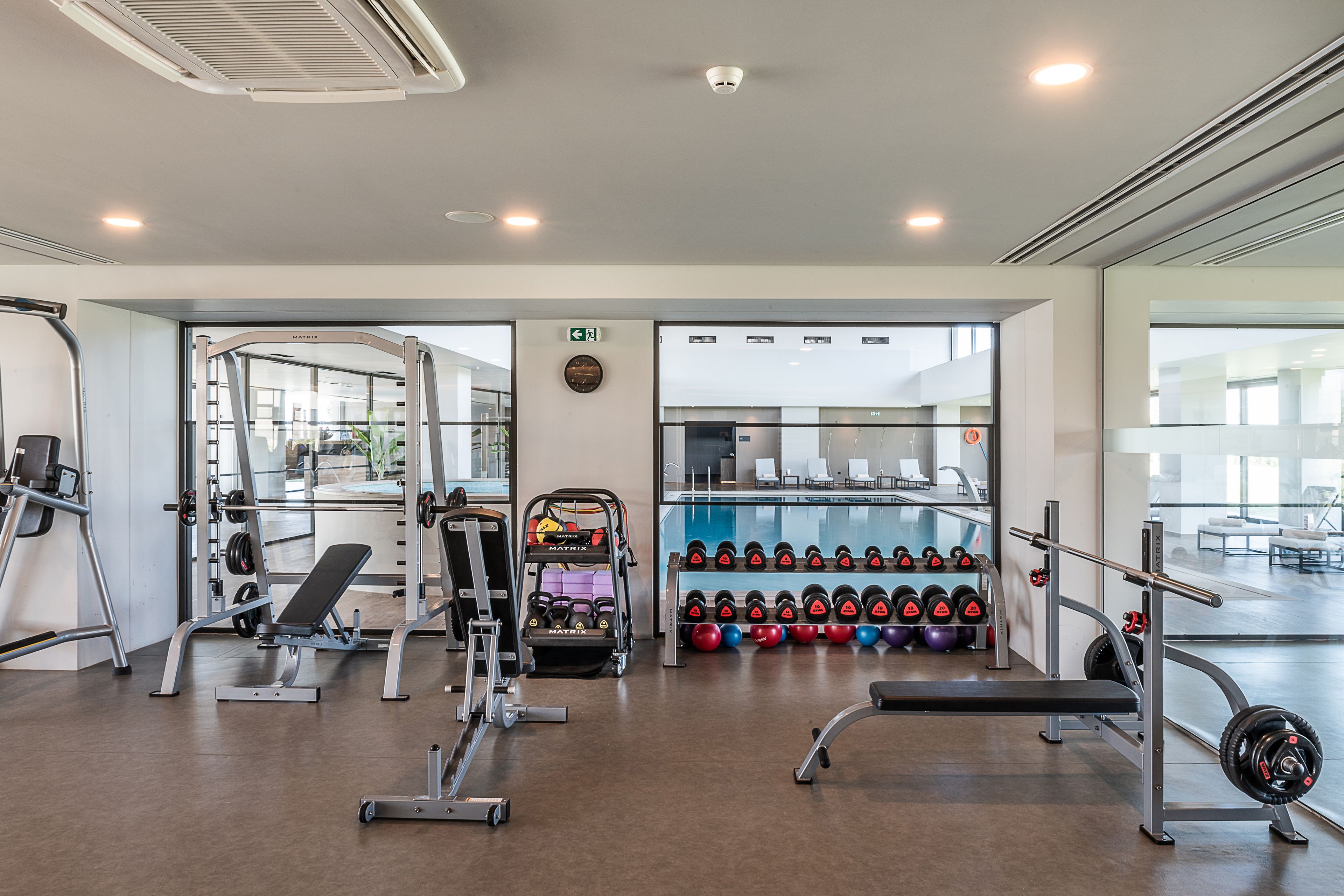 A modern gym with weightlifting equipment, benches, and dumbbells.