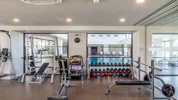 A modern gym with weightlifting equipment, benches, and dumbbells.