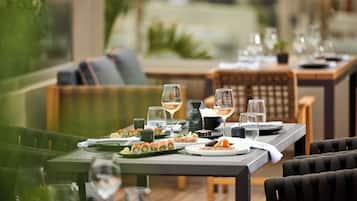 A dining area with a table set for two, featuring sushi, a bottle of wine, and a vase.