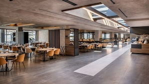 A spacious restaurant with high ceilings, large windows, and modern furniture. - Euphoria Resort - All Inclusive (Platanias)