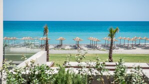 A beachside view with umbrellas and lounge chairs, a clear sky, and a calm sea. - Euphoria Resort - All Inclusive (Platanias)