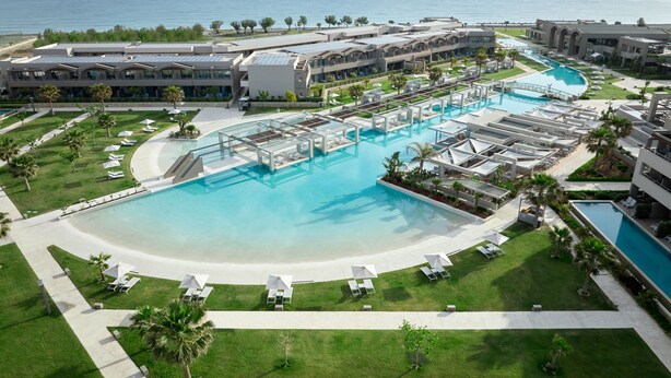 A resort with a large central pool, multiple sun loungers, and a view of the ocean. - Euphoria Resort - All Inclusive (Platanias)