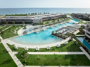 A resort with a large central pool, multiple sun loungers, and a view of the ocean. - Euphoria Resort - All Inclusive (Platanias)