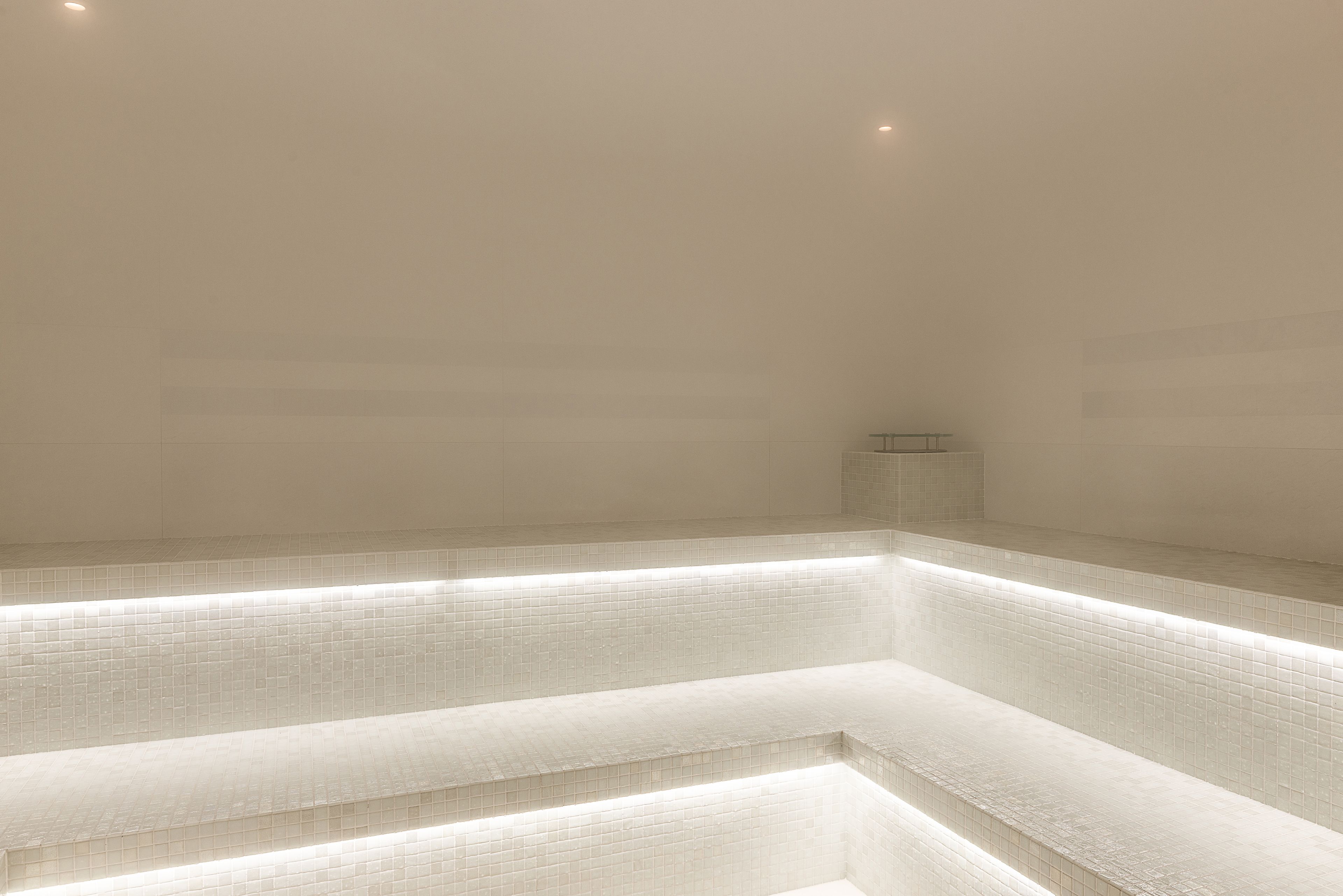 A modern, minimalist bathroom with tiled walls and a bench.