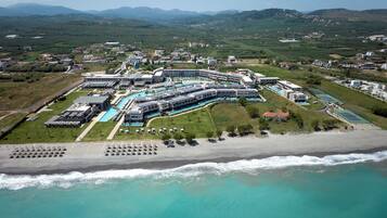 An aerial view of a resort with multiple buildings, a swimming pool, and a beach.