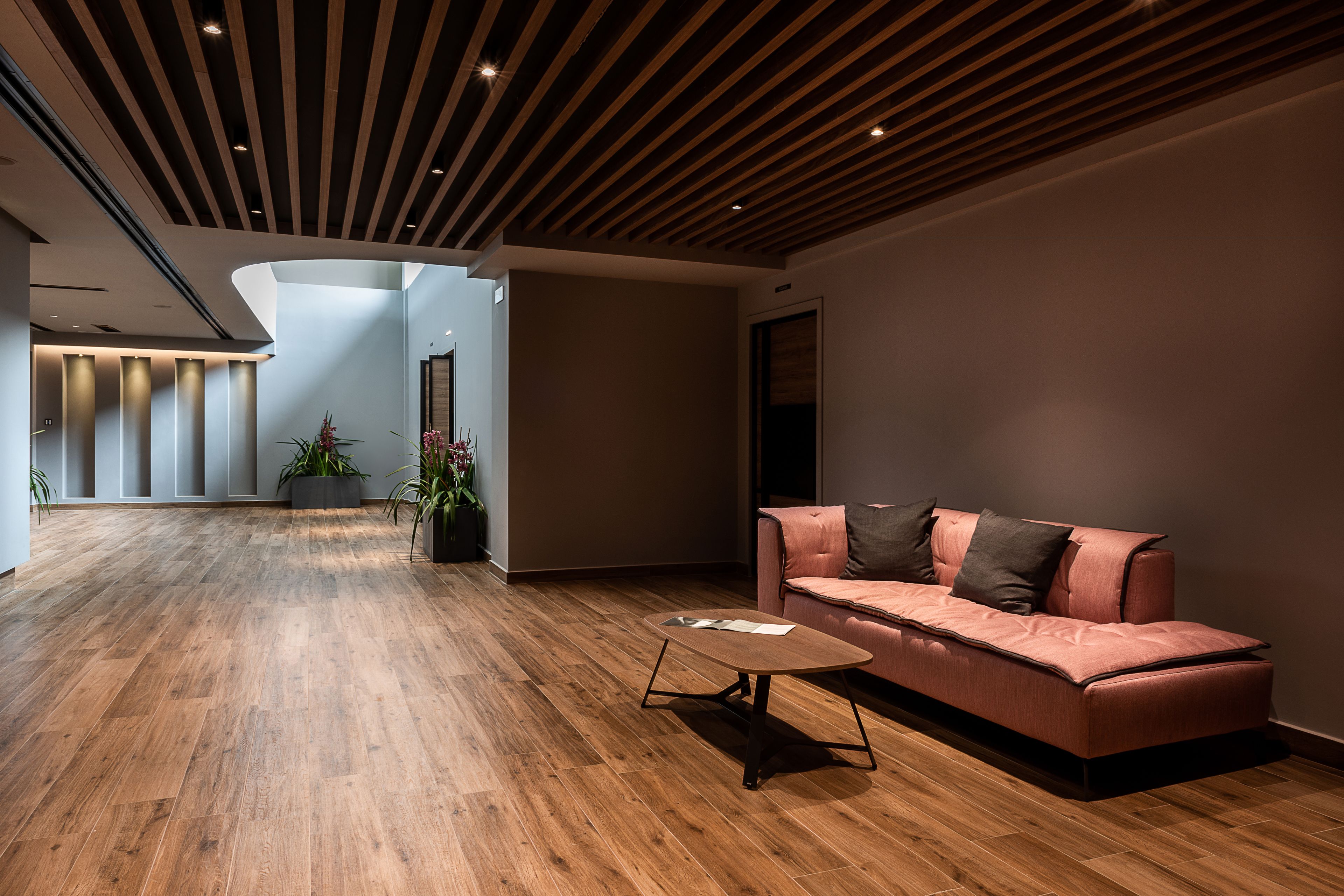 A modern interior with a wooden floor, a pink sofa, and a coffee table.
