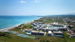 An aerial view of a coastal resort with multiple buildings, a beach, and a clear blue sky. - Euphoria Resort - All Inclusive (Platanias)