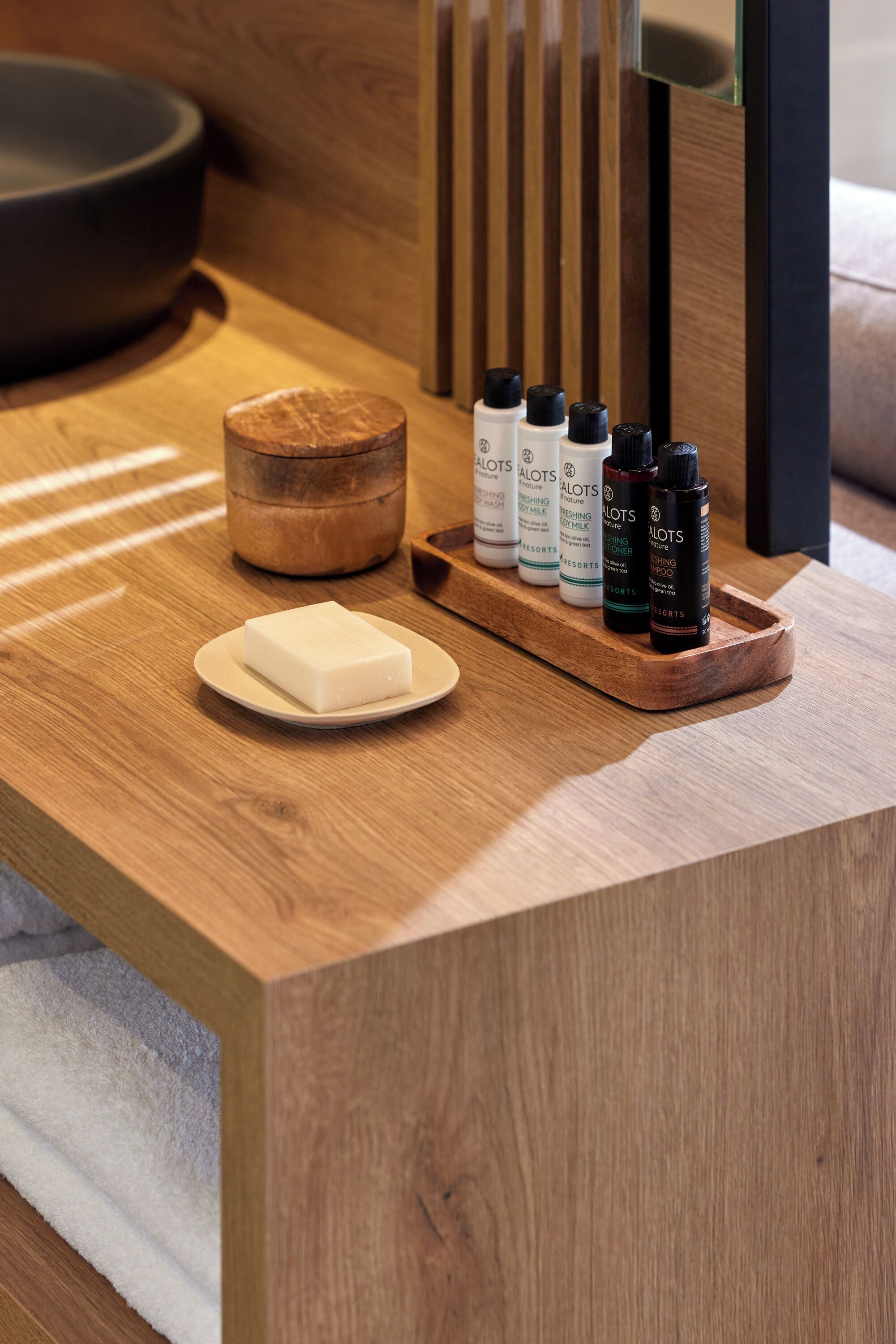 A wooden reception desk with a soap dish, a wooden bowl, and several bottles of lotion.