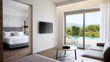 Habitación de hotel moderna con cama, sofá, una mesita, televisor y balcón con vista a la piscina.