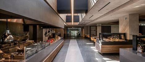 A modern hotel lobby with a central walkway, a reception desk, and a buffet area.