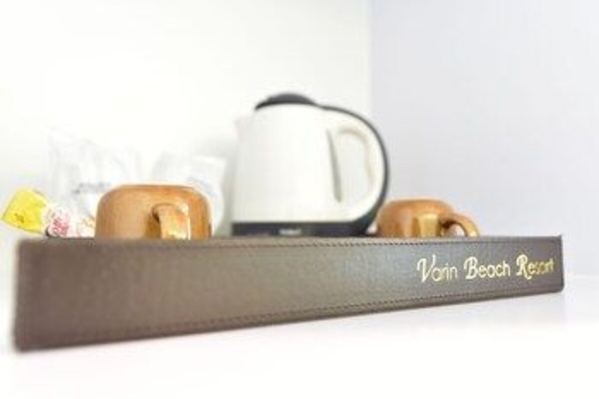 Una bandeja con una cafetera y dos tazas, con la etiqueta 'Vain Beach Resort'.