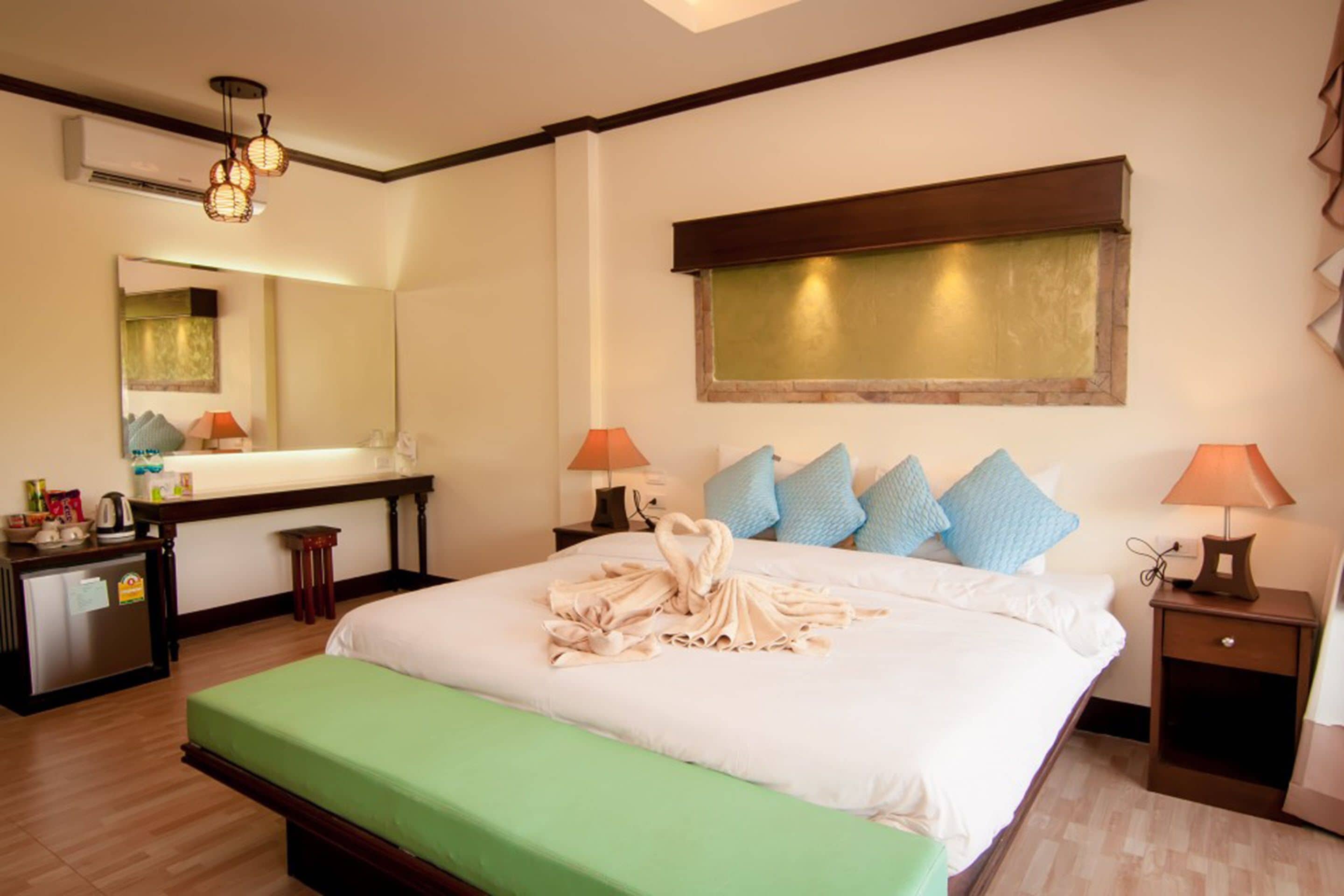 Ein Hotelzimmer mit einem großen Bett, Nachttischen, einem Schreibtisch und einem Spiegel.