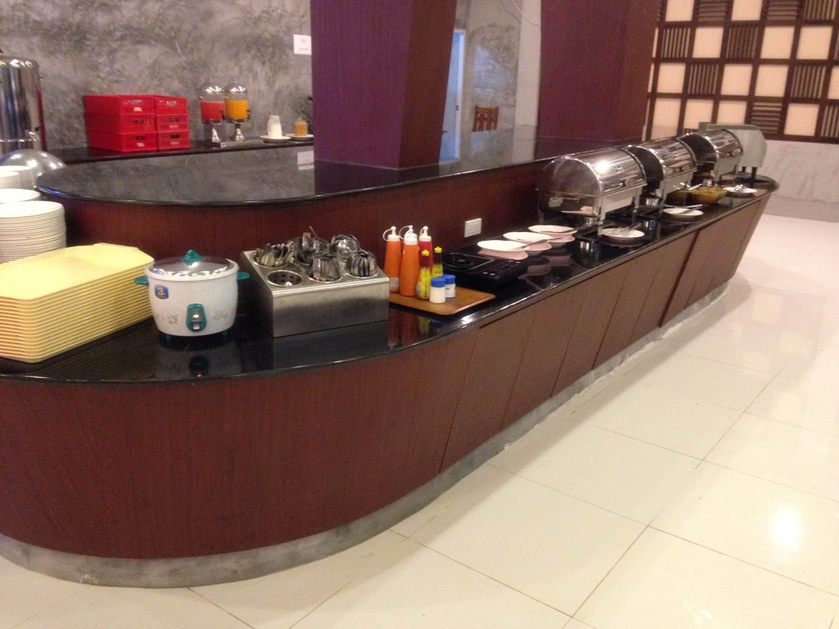 A breakfast bar with a coffee maker, tea kettle, and juice dispensers.