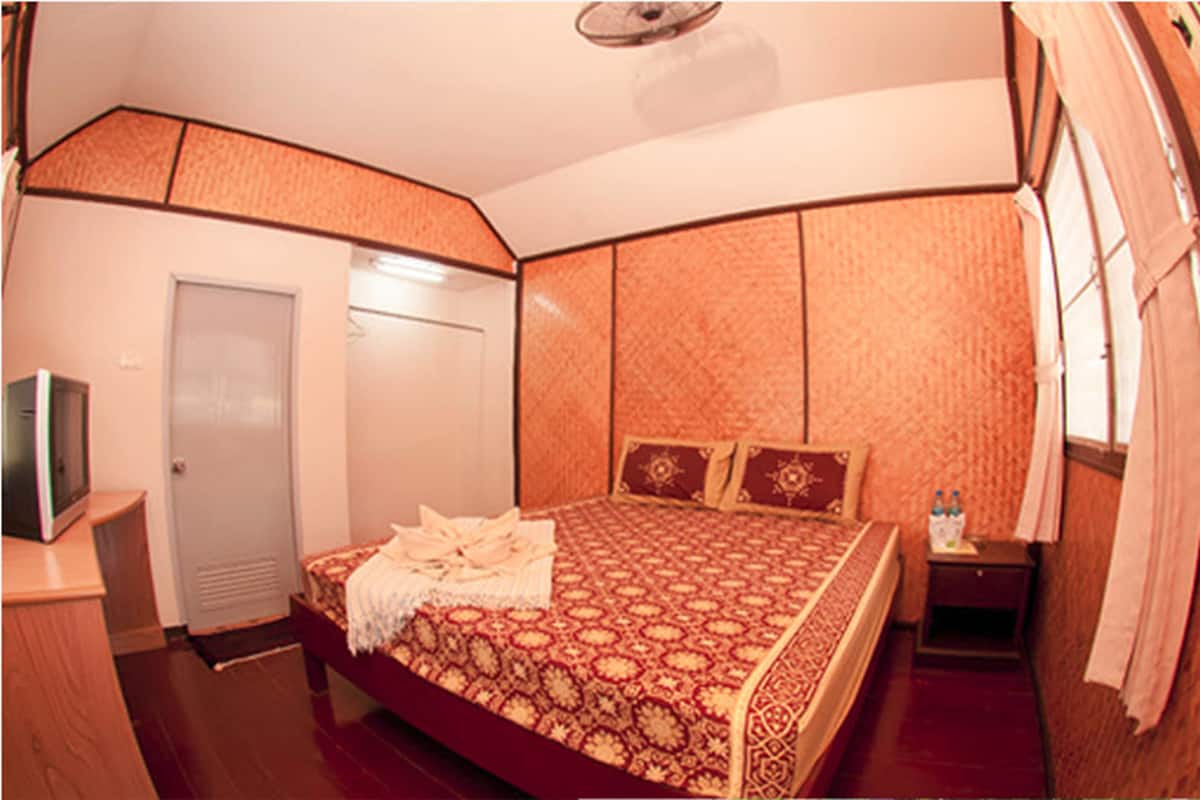 A bedroom with a large bed, a bedside table, a wardrobe, and a television.