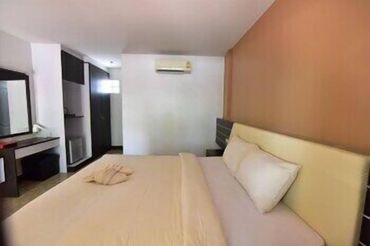 A hotel room with a bed, a desk, a mirror, and a wardrobe.