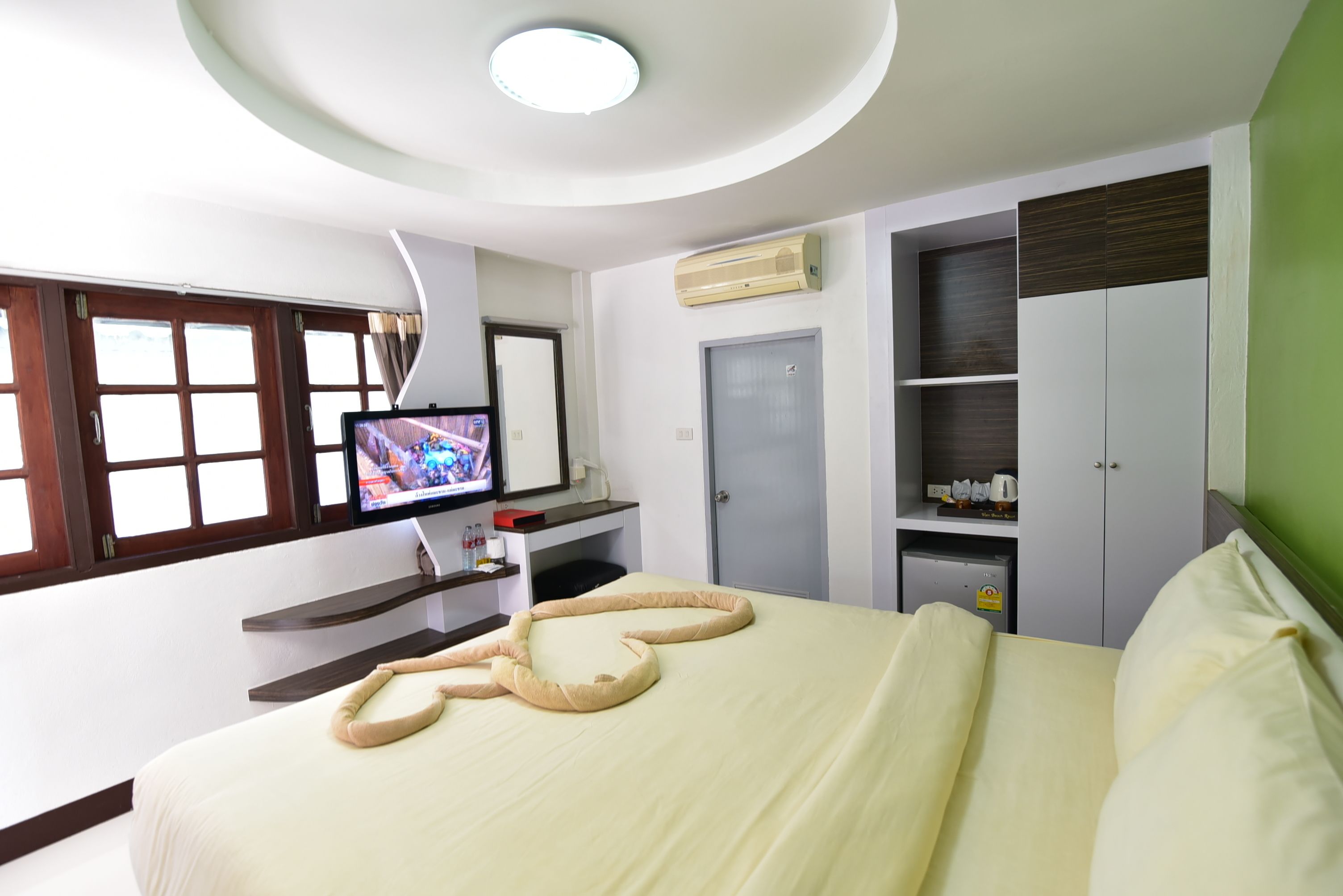 Une chambre d’hôtel équipée d’un lit, d’une télévision, d’une armoire et d’une petite kitchenette.