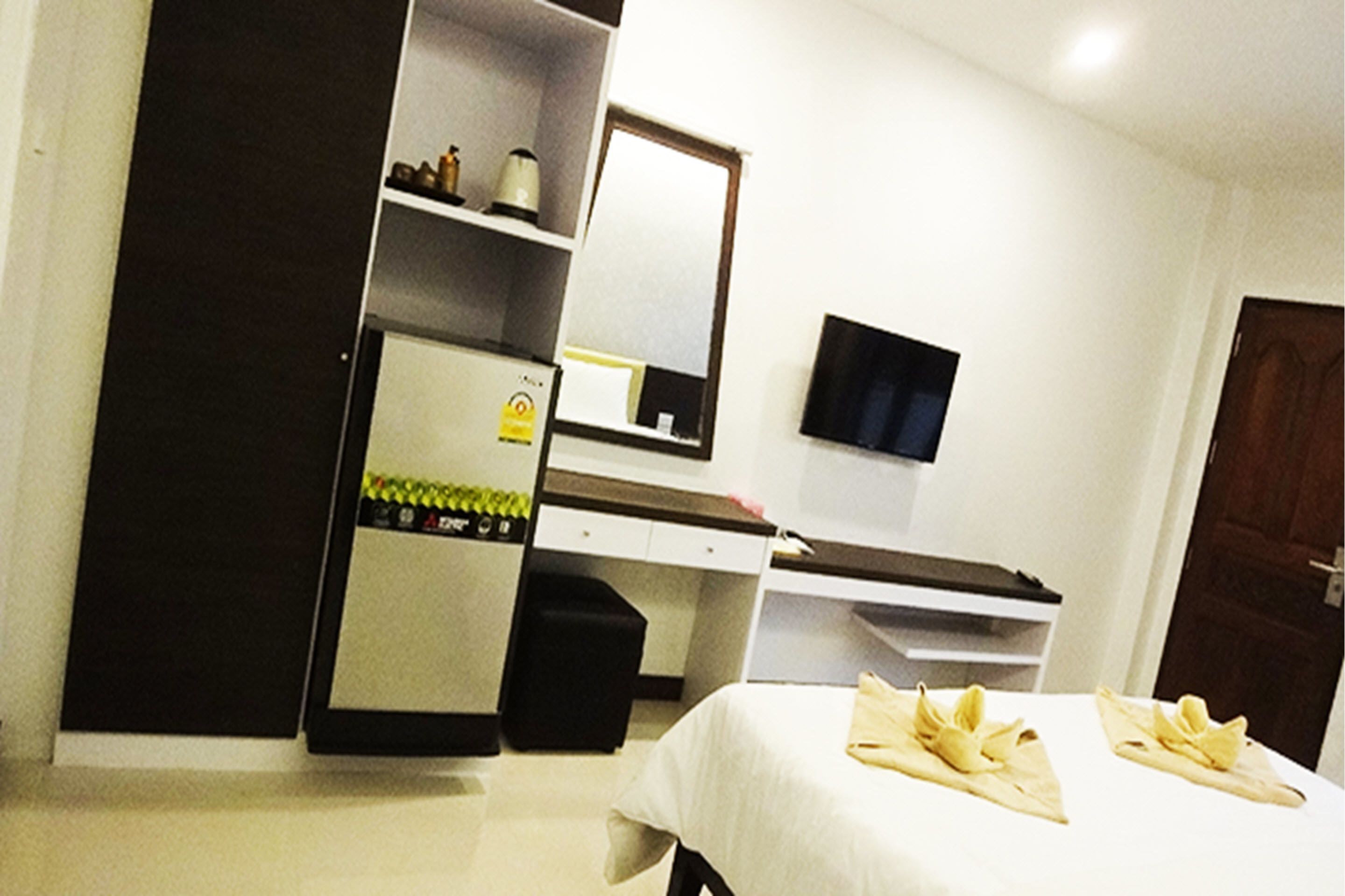 Habitación de hotel con cama, escritorio, silla, armario, televisor y puerta.