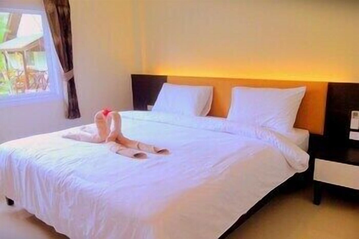 A hotel room with a bed, a nightstand, and a window with curtains.