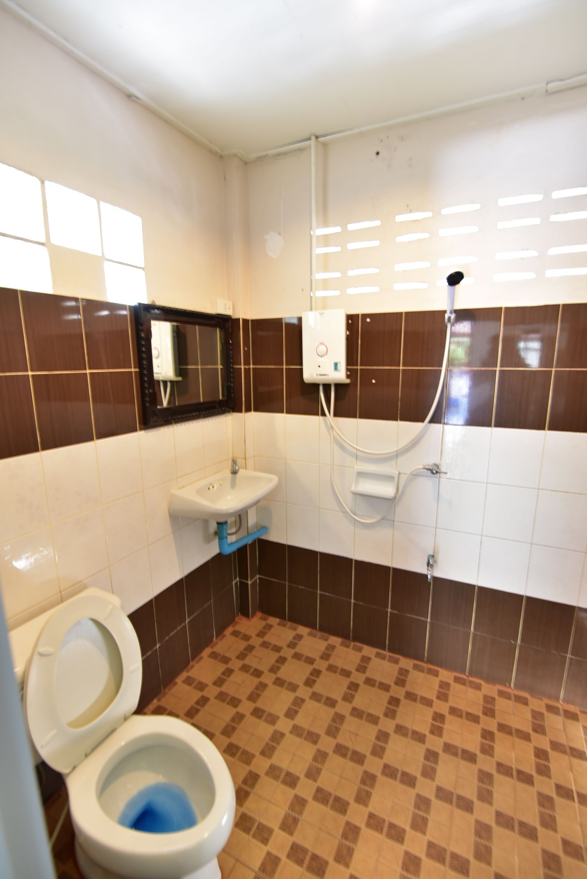 Un baño con dos inodoros, un lavabo y una ducha.