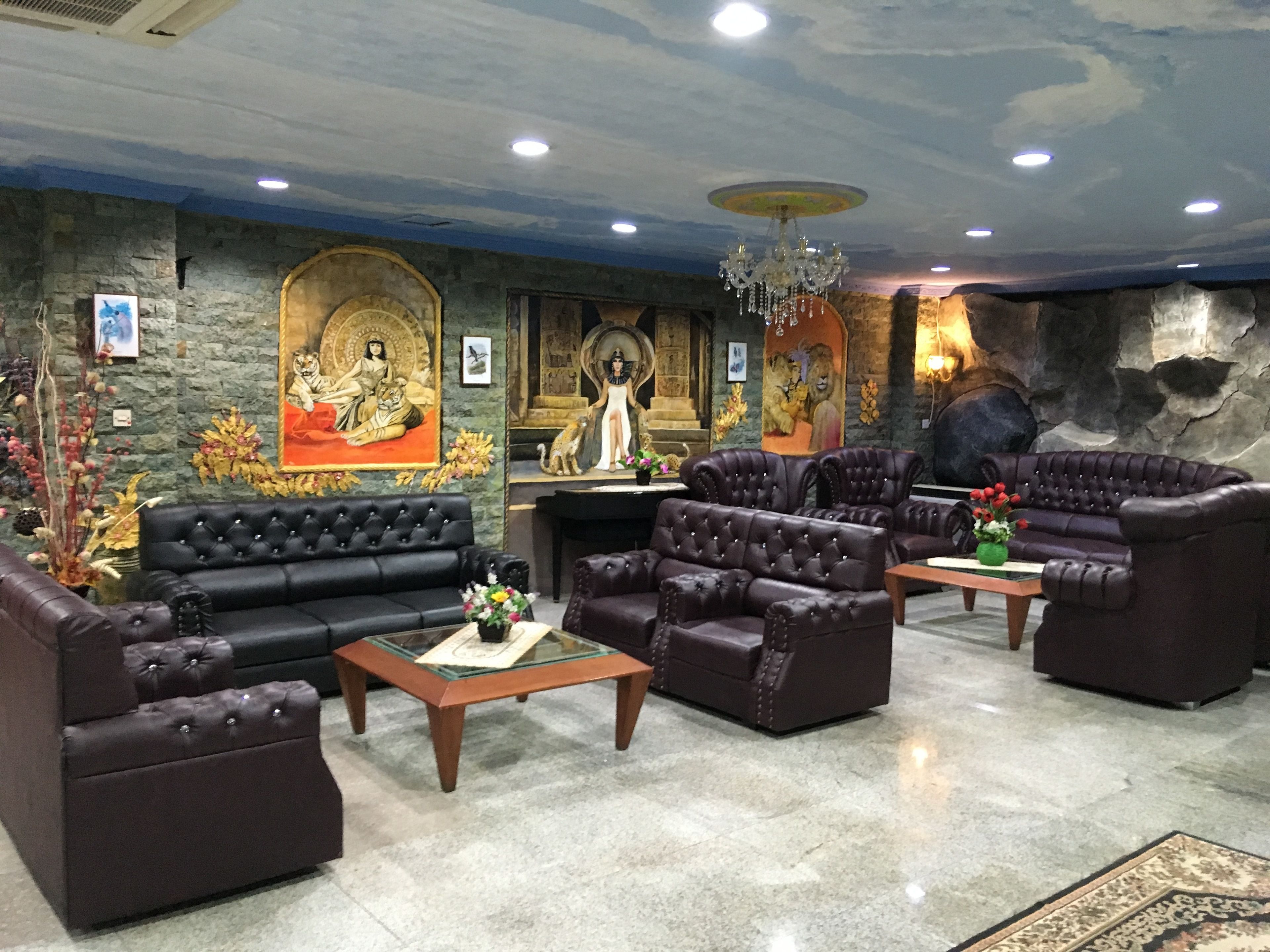 A lobby with a stone wall, a chandelier, and a Buddha statue.