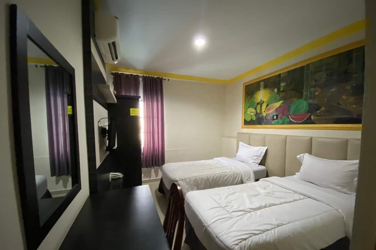 Habitación de hotel con dos camas, un espejo grande, un escritorio y un cuadro en la pared.