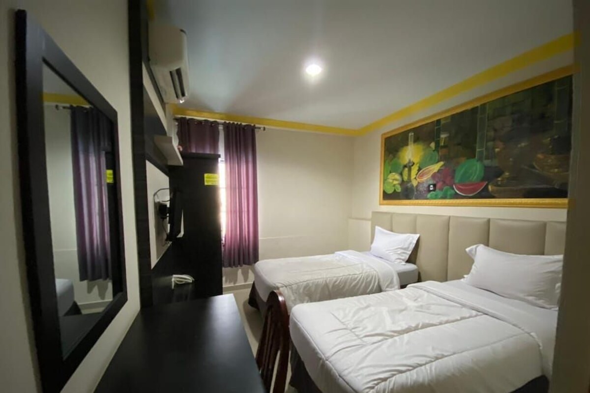 Habitación de hotel con dos camas, un escritorio, un espejo y un cuadro en la pared.