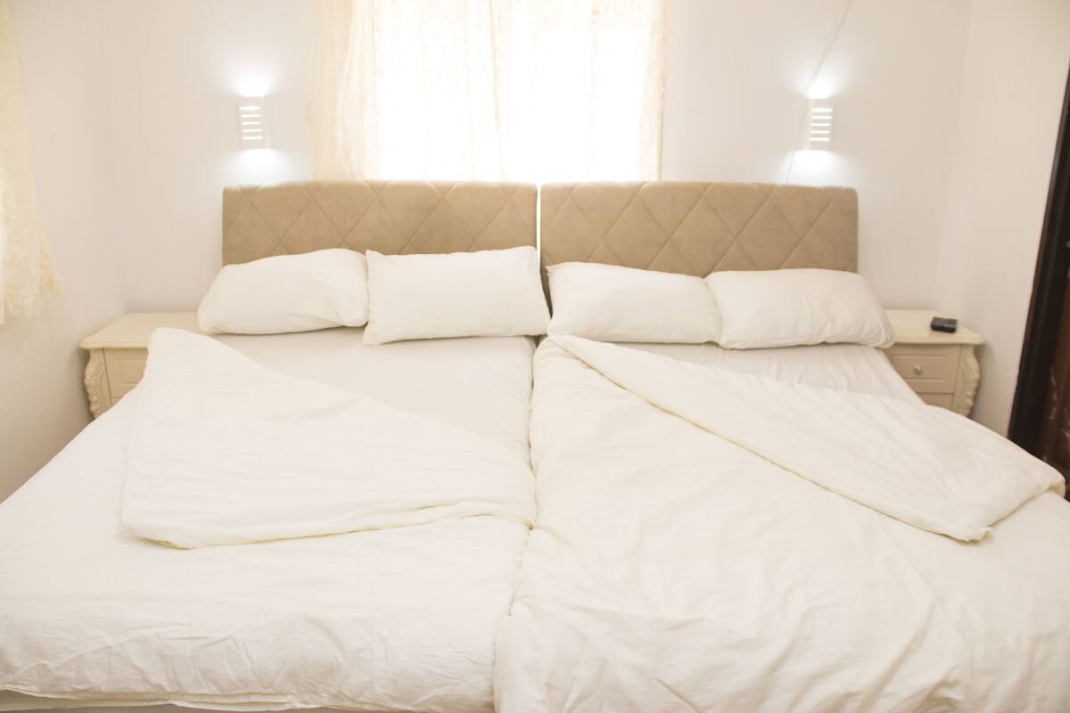 A double bed with white bedding, a headboard, and bedside tables with lamps.