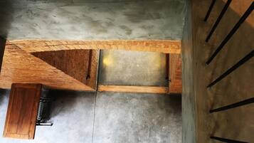 A top-down view of a room with a concrete floor, a wooden bench, and a small wooden table.