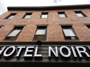 A hotel facade with a brick exterior and multiple windows. - Hotel Noir (Chiang Mai)