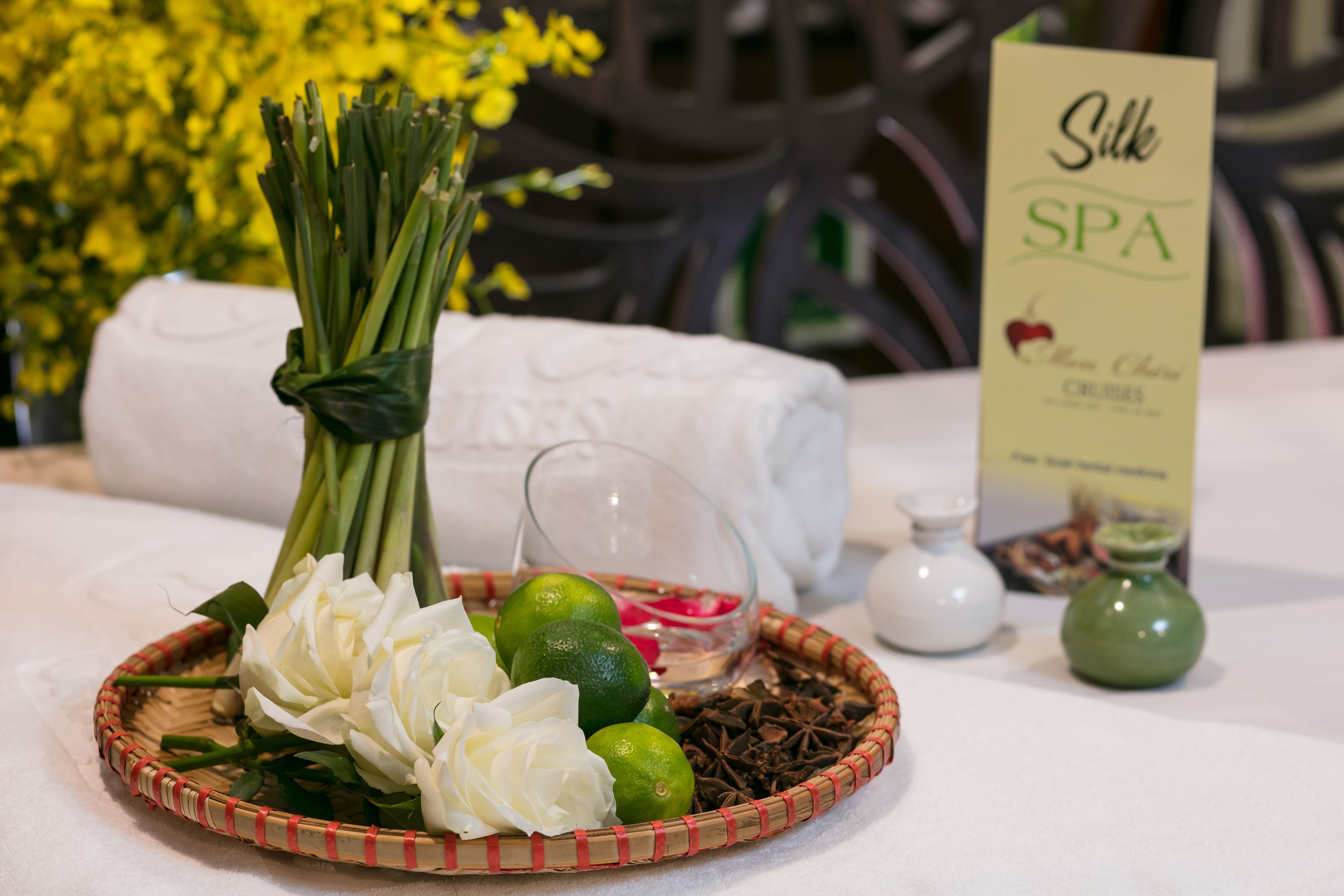 Un ambiente de spa con una bandeja de mimbre que contiene flores blancas, limones y hierbas secas.