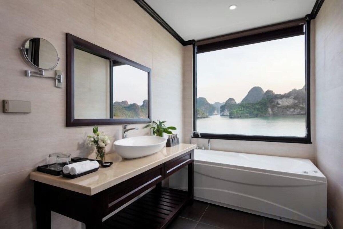 Une salle de bain moderne dotée d’une grande fenêtre, d’une baignoire et d’un meuble-lavabo avec un miroir et un évier.