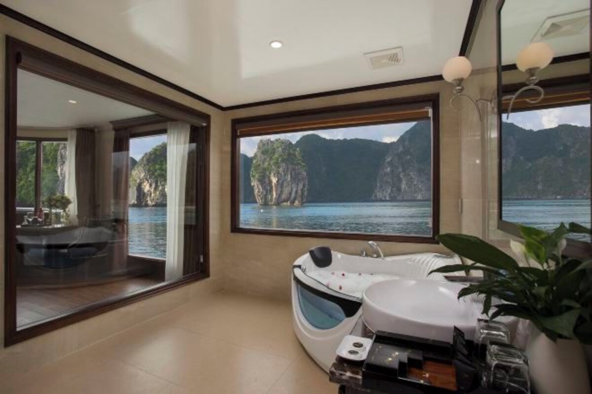 A modern bathroom with a bathtub, a sink, and a large window offering a view of a mountainous landscape.