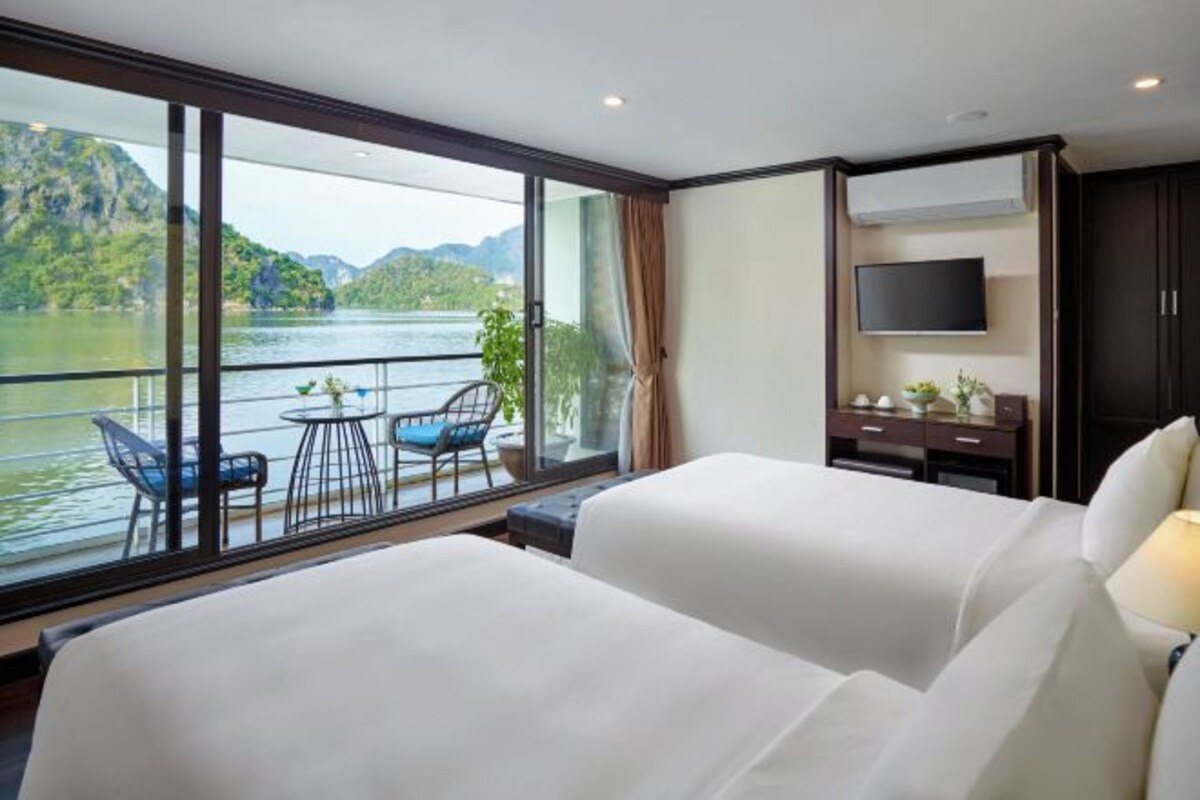 A hotel room with a large window, a bed, a TV, a desk, and a chair.