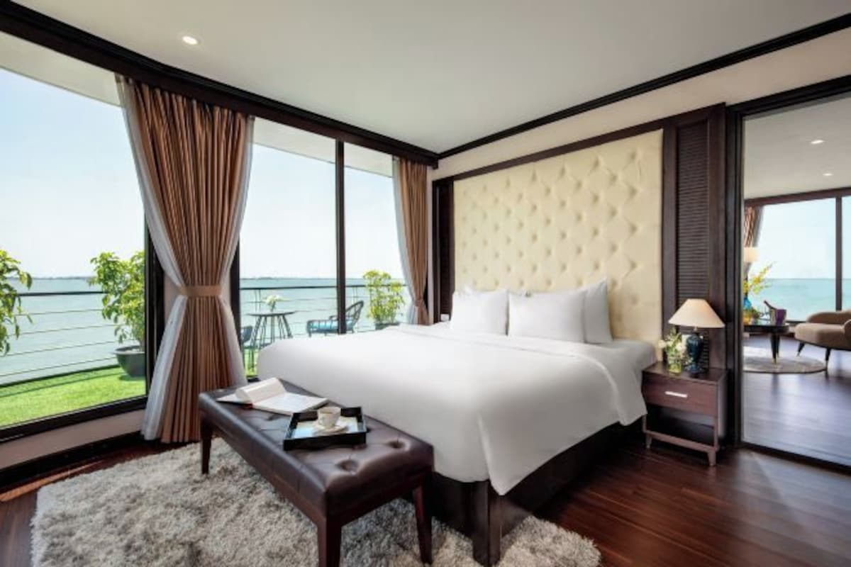 Una habitación de hotel con una cama grande, vistas al mar, un balcón y un diseño moderno.